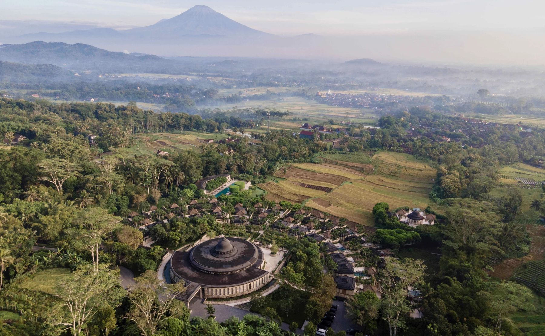 Amanjiwo viewed from the wooded hillside behind the resort, with its circular pavilion, curved suites and the valley beyond