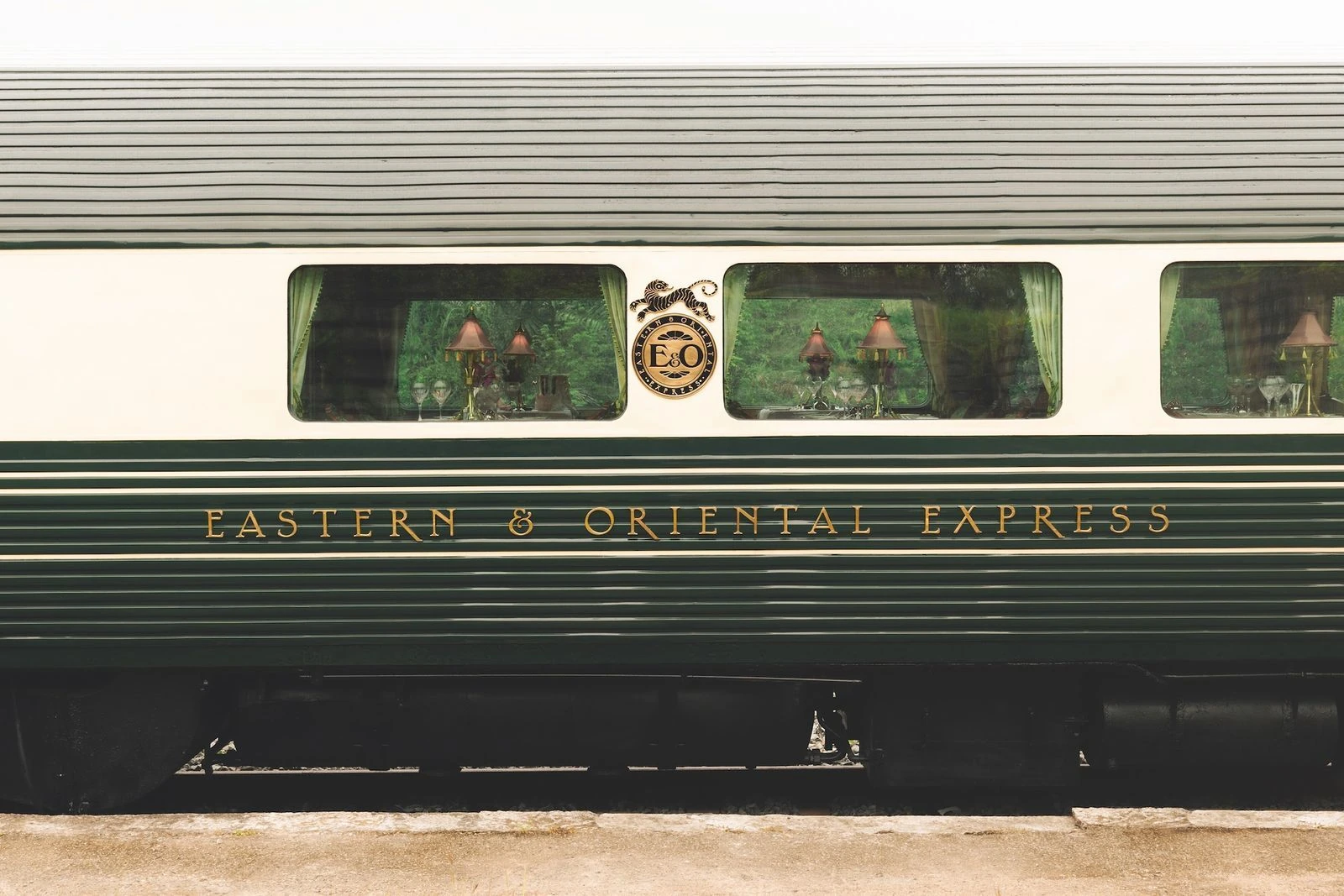 A straight side view of the green and cream Eastern and Oriental Express carriage, with its complete gold lettering and crest